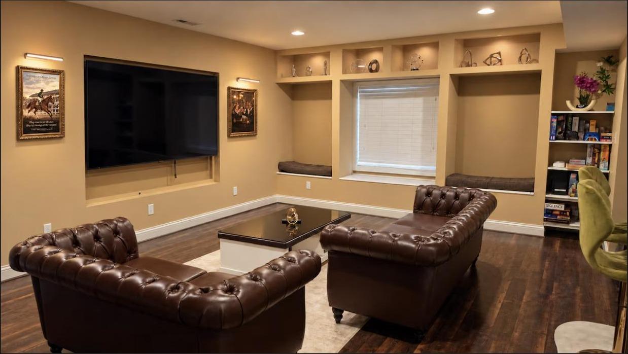 The Bourbon Lounge with a large TV, Chesterfield sofas, and Kentucky-themed art