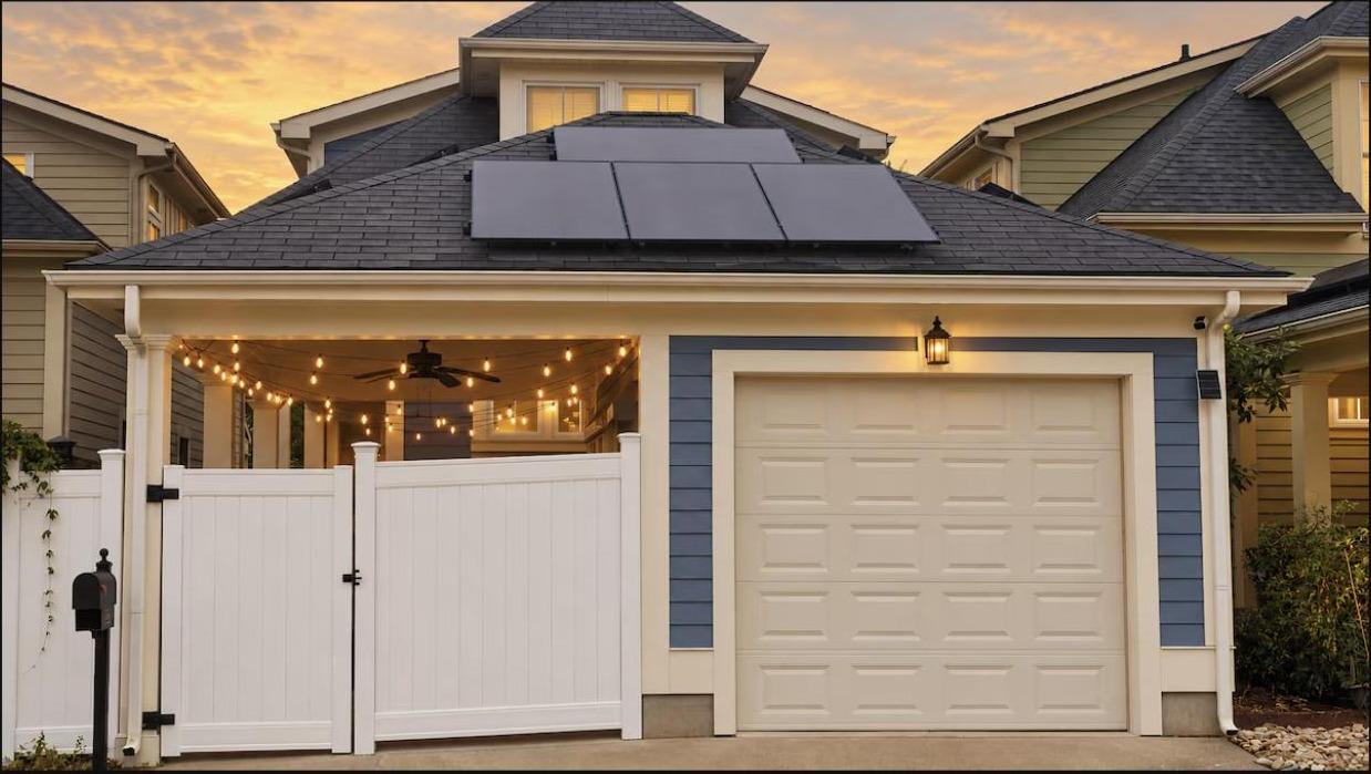 Rear exterior at dusk showing the garage, solar panels, and gated patio entrance