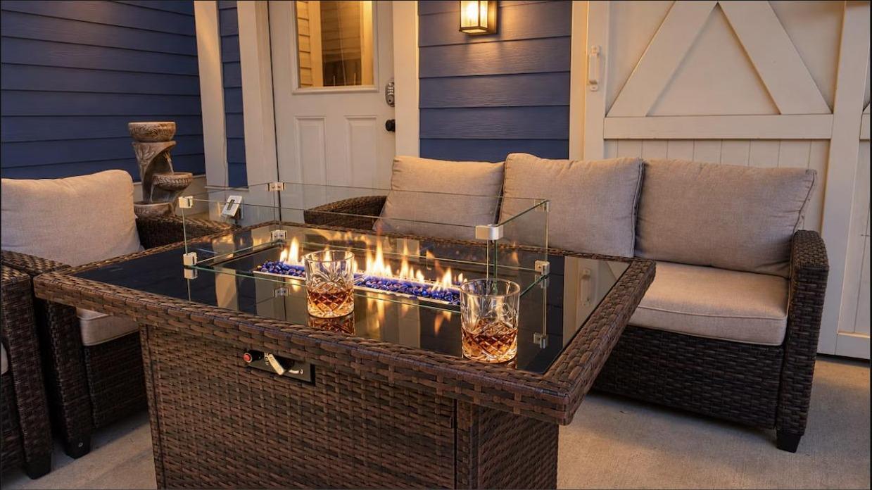Two glasses beside the lit fire pit on the covered patio