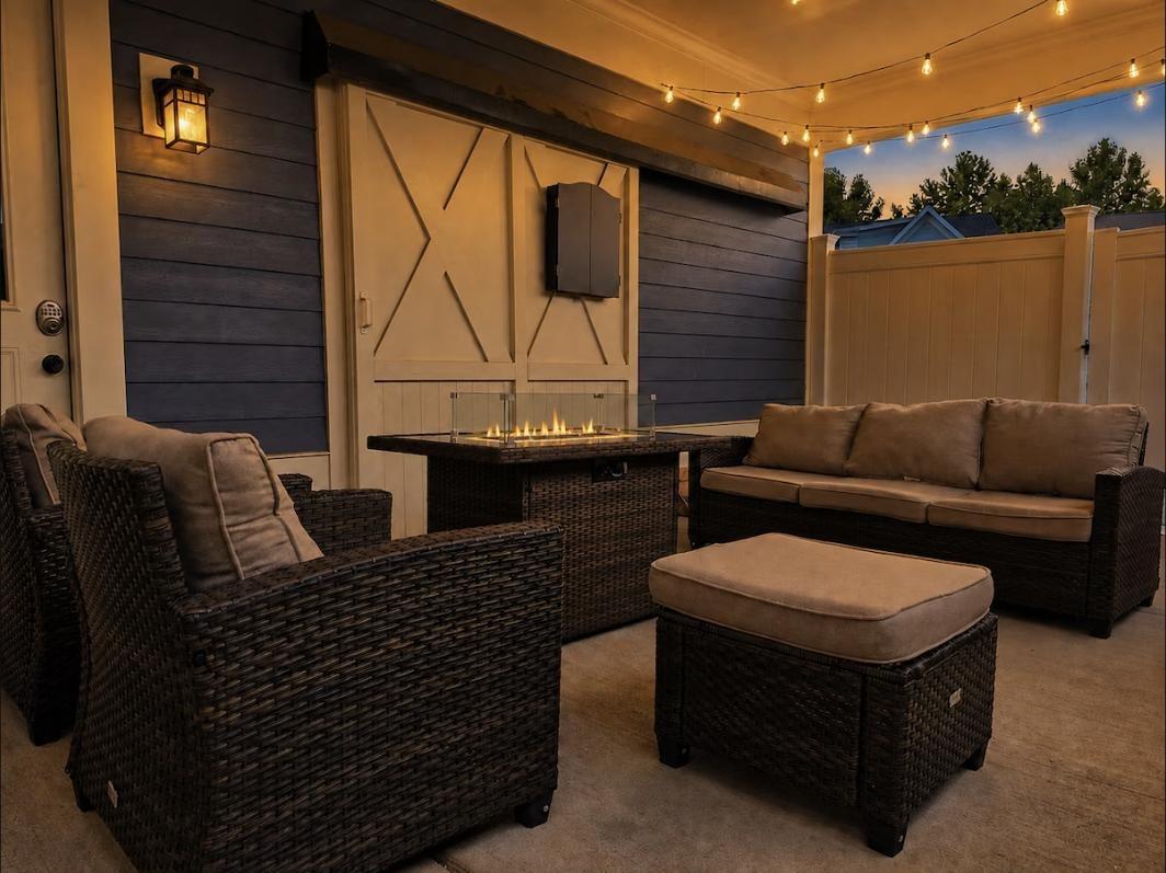 Covered patio with a fire pit, wicker seating, and string lights at dusk